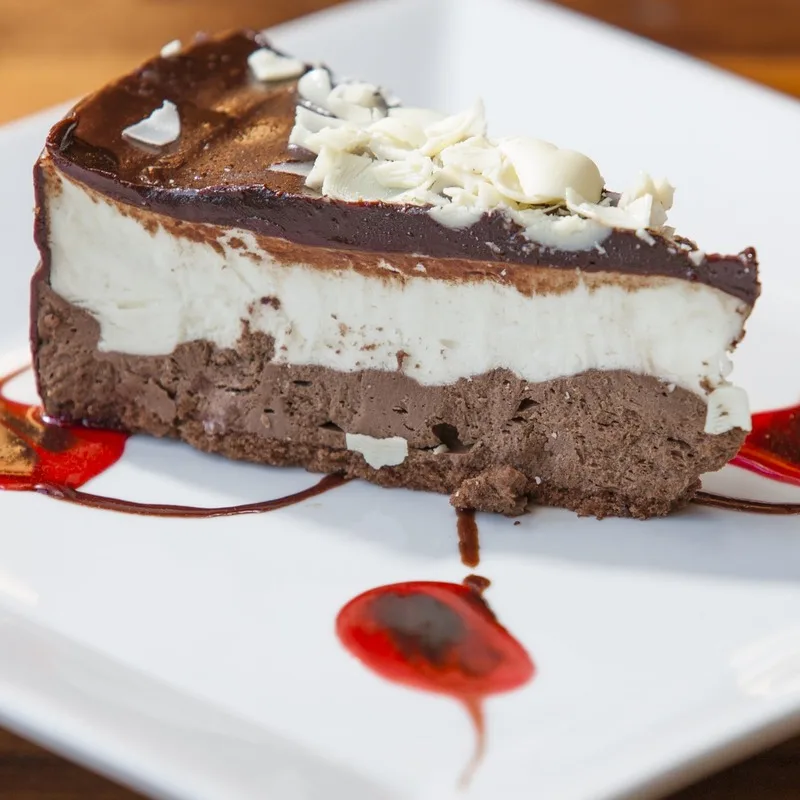 Slice of cheesecake plated with chocolate drizzle