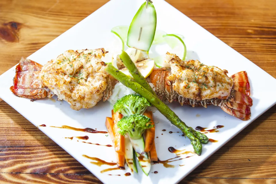 Stuffed lobster tails plated with balsamic drizzle